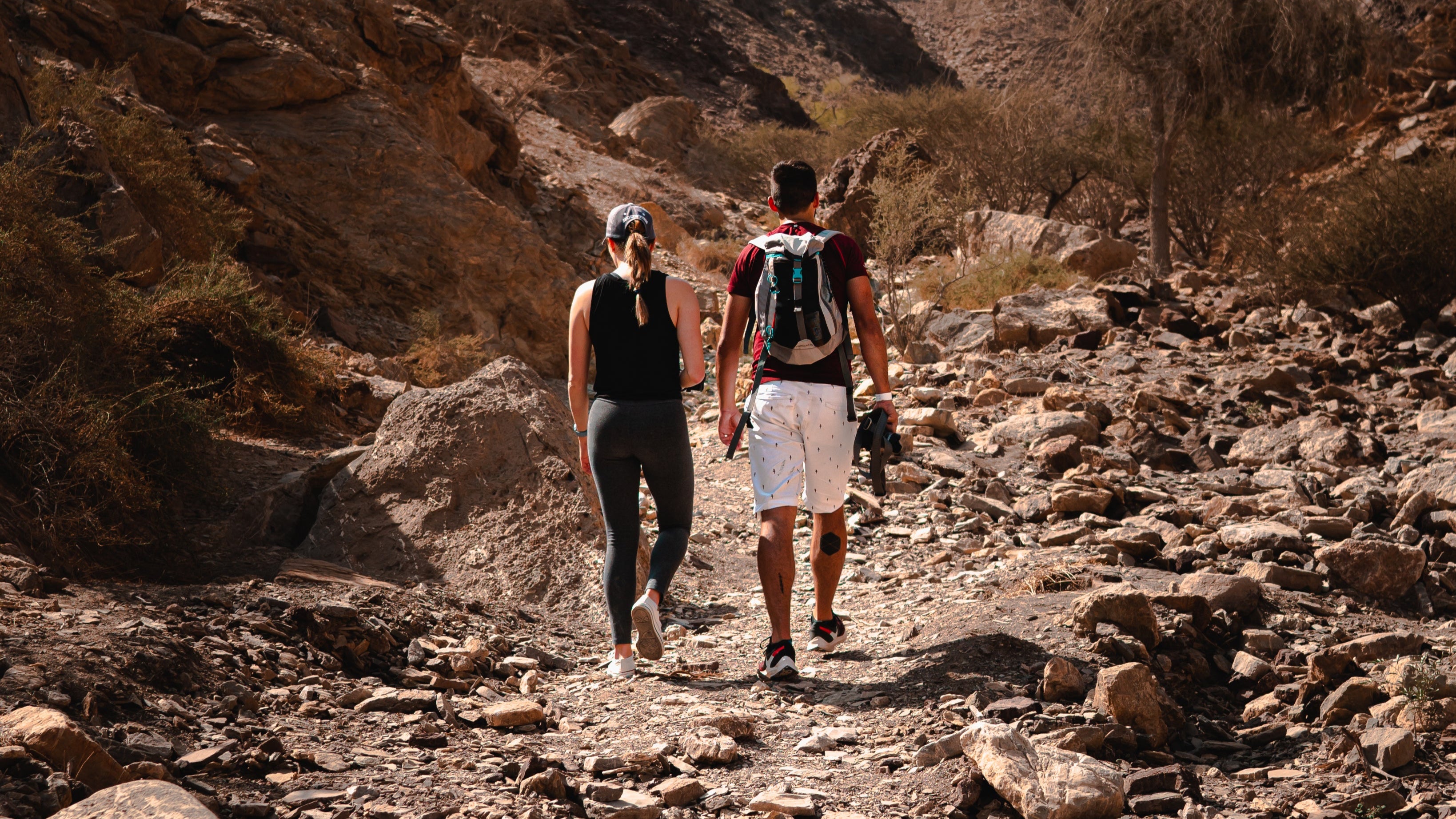 two-people-hiking-on-a-rustic-trail wearing backpacks